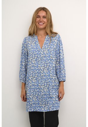 Tunique bleue avec un motif botanique en blanc et beige, à col en V et manches 3/4, fabriquée en tissu léger.