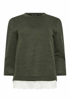 Top de punto de manga larga de color verde oscuro con cuello redondo y encaje blanco asomando del dobladillo, diseño en capas.