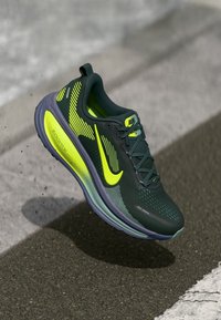 Nike bėgimo bateliai su tamsiai žalia tinklinė viršutine dalimi, ryškiai geltonomis akcentais, tekstūruotu padu ir išraiškingu swoosh logotipu. Lengva amortizacija.