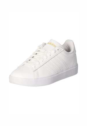 Hvid Adidas sneaker med snørelukning foran, tre side striber, polstret krave og gyldt Adidas-logo på tungen.
