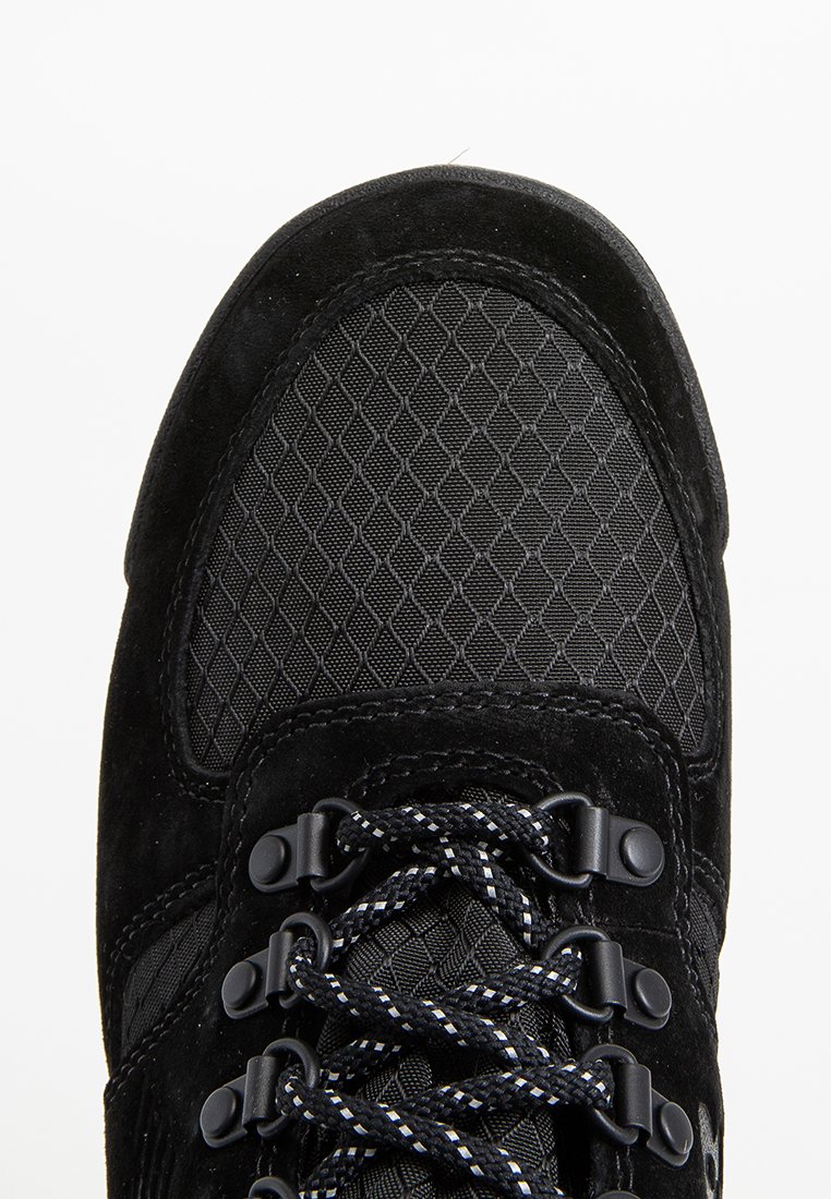 Scarpa da trekking nera con upper in mesh testurizzato con motivi a diamante, dettagli in suede, hardware nero e lacci spessi con filamenti bianchi a contrasto.