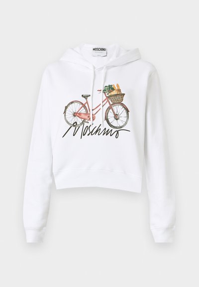 White cropped hoodie featuring a pink bicycle graphic carrying groceries, with a signature in black below the design. Material appears soft and smooth.