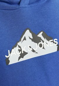 Blauer Hoodie mit einem Grafikdruck von Bergen in Schwarz und Weiß, mit "JACK & JONES" in Weiß und "CONSTRUCTED, INNOVATIVE, UTILITY" darunter.