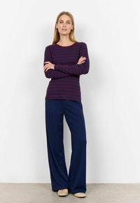 Långärmad marinblå randig topp med vinröda horisontella linjer, tillsammans med vida marinblå byxor med en mjuk textur och avslappnad passform.