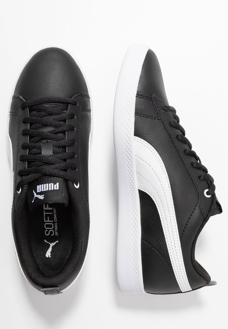 Zapatillas de cuero negras con detalles blancos, que presentan un acabado texturizado, punta redonda y diseño de cordones. Suela de goma blanca, con la marca visible en el interior.