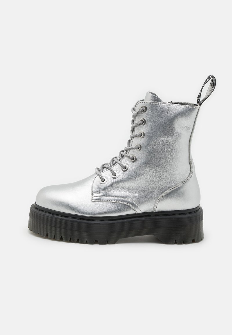 Botte de combat montante en cuir métallisé argenté avec semelle noire épaisse et talon à boucle d'extraction sur fond blanc.