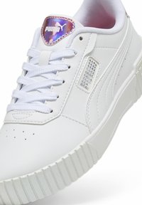Sneaker sintetico bianco con suola texturizzata, punta rotonda e perforazioni. Presenta una patch con logo viola e argento sulla linguetta.