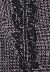 Woven fabric featuring a black and gray checkerboard pattern with large, dark text accents. Soft texture with a detailed design.