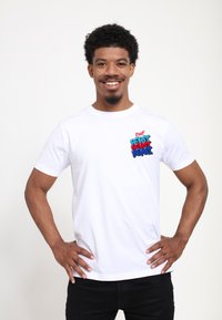 Bílý bavlněný tričko s barevným grafickým motivem "Drink! Pepsi" na levé straně hrudi. Krátké rukávy a standardní design s kulatým výstřihem.