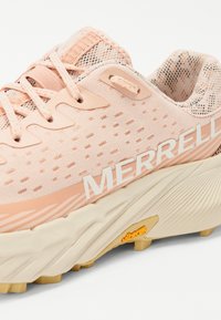 Baskets de course rose clair avec dessus en maille, accents texturés et logo "MERRELL" bien en vue. La semelle avec crans présente un détail jaune Vibram.