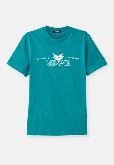 T-shirt de algodão turquesa com decote redondo, mangas curtas e texto impresso em branco incluindo "VERSACE" e um motivo decorativo de chamas.