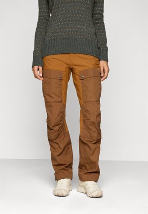 Brune cargo bukser med flere lommer, kontrasterende paneler og trykknaplukninger. Kombineret med en struktureret mørkegrøn sweater.