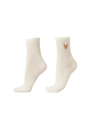 Krémově zbarvené ponožky do poloviny lýtek s žebrovanými lemy, jedna s malou vyšívanou tváří corgi psa blízko horní části.