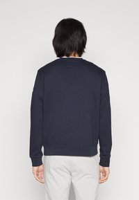 Felpa blu navy, misto cotone, collo rotondo, maniche lunghe, polsini e orlo a costine. Nessun motivo o logo visibile. Vista posteriore.