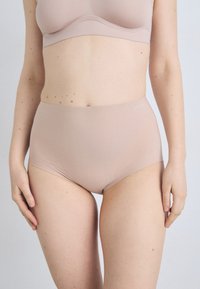 Beige høytalere truser laget av glatt stoff, med sømløst design og en komfortabel elastisk midjebånd, minimal detaljering.