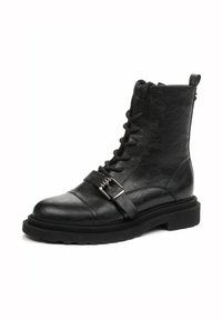 Bottine en cuir noir avec un bout rond, un laçage à l'avant et un accent en boucle en argent. Semelle épaisse pour plus de stabilité.