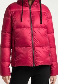Ljusrosa puffjacka med dragkedja fram, huva och svarta snoddar. Har horisontell quiltad textur och sidofickor.