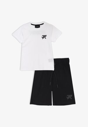 T-shirt bianca in cotone con logo nero sul petto, abbinata a pantaloni corti neri con vita elastica e accento logo sulla gamba sinistra.
