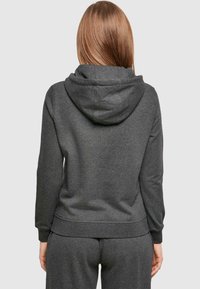 Donkergrijze hoodie van gestructureerde stof, met een grote capuchon, ribgebreide manchetten en een ontspannen pasvorm, gecombineerd met bijpassende trainingsbroeken.