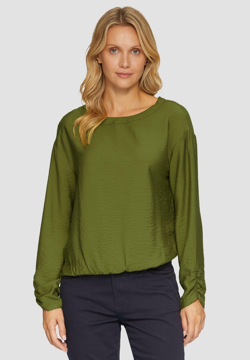 Olijfgroene blouse met lange mouwen en ronde halslijn, een gladde textuur en gathered accenten bij de mouwen, gecombineerd met donkere broeken.