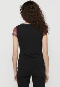 T-shirt nero con maniche corte texture rosse. Presenta un colletto rotondo e un retro liscio. Il tessuto sembra morbido e aderente.