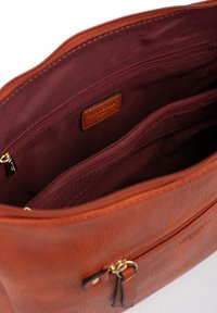 Borsa a mano in pelle marrone con finitura testurizzata. L'interno presenta una fodera color bordeaux scuro e molteplici tasche con zip per l'organizzazione.