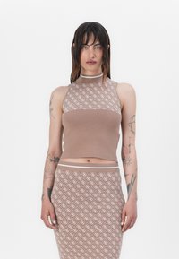 Crop top en tricot marron à col montant, avec un motif blanc subtil ; associé à une jupe ajustée assortie.
