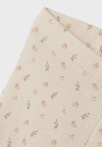 Wyszczerbione legginsy w miękkim różowym materiale, z małymi kwiatowymi wzorami w zielonym i niebieskim kolorze, o gładkiej fakturze i wygodnym pasie.