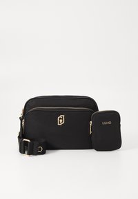 Schwarze Stoff-Crossbody-Tasche mit goldenen Beschlägen, die ein Logo-Detail, Reißverschlussfächer und ein zusätzliches passendes Etui bietet. Verstellbarer Riemen inklusive.