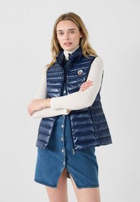 Marineblaue Steppweste mit hohem Kragen und Frontknöpfen. Sie zeichnet sich durch ein Logopatch, horizontale Steppung und eine taillierte Silhouette aus.