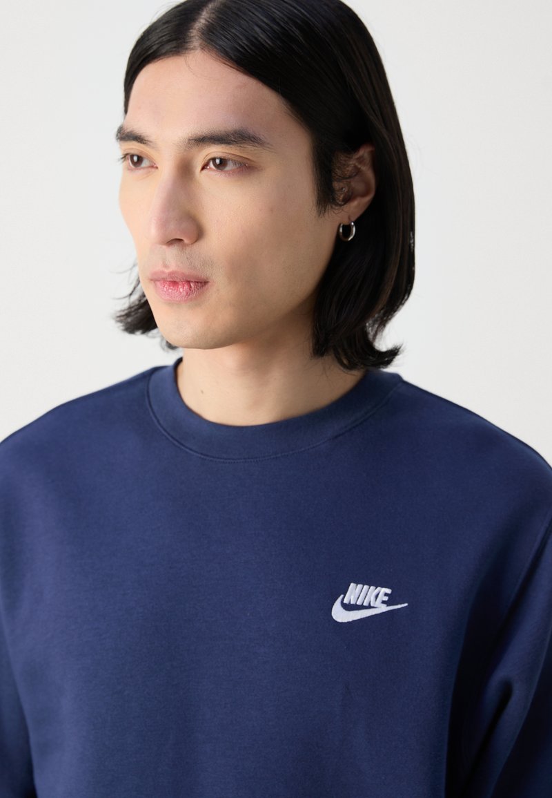 Marinblå Nike sweatshirt med rund hals, mjuk textur och en liten vit logotyp på vänster bröst.