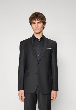 Black suit jacket with a tailored fit, notched lapels, two buttons, and a white pocket square. Fabric has a smooth, matte texture.