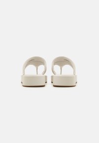 White platform sandals with wide straps, a smooth finish, and an open back design. The bottom features a textured, contrasting rubber sole.