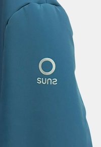 Giacca imbottita blu con texture liscia, spalle arrotondate e logo riflettente sul braccio sinistro.