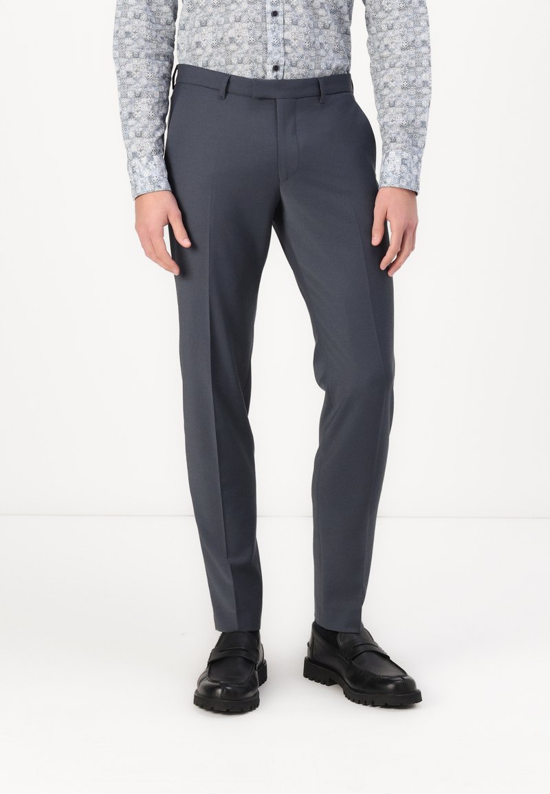 Pantalons gris ajustés avec une texture lisse, un design slim fit et des passants de ceinture, associés à des chaussures noires à enfiler avec une finition polie.