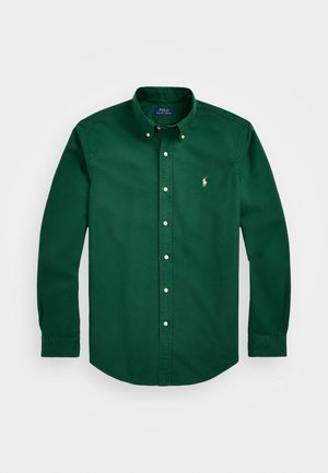 Chemise verte à manches longues en coton. Présente un col classique, des manches longues et un petit logo brodé sur la poche gauche.