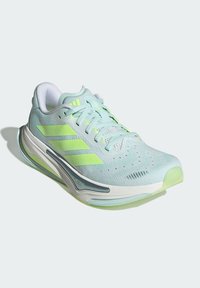 Lichtblauwe sneakers met groene accenten, bovenwerk van mesh, gevoerde kraag en een gestructureerde zool. Beschikt over drie kenmerkende strepen en ventilatiegaten.