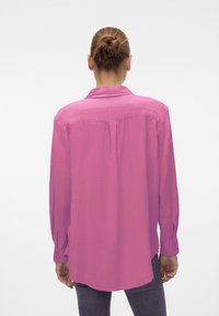 Long-sleeve, light pink shirt with a subtle sheen, collared neckline, and buttoned cuffs, featuring a relaxed fit and split hem design.