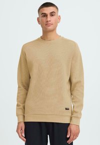 Maglione beige a maniche lunghe con un design testurizzato a coste. Collo rotondo e polsini; presenta un piccolo etichetta del marchio all'orlo.