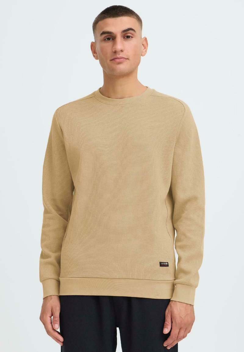 Maglione beige a maniche lunghe con un design testurizzato a coste. Collo rotondo e polsini; presenta un piccolo etichetta del marchio all'orlo.