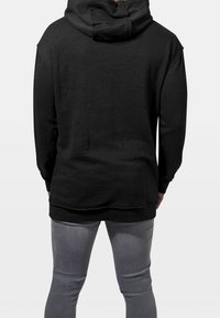 Sudadera negra con capucha, de corte relajado, tela texturizada y un bolsillo tipo canguro. La parte trasera cuenta con una capucha amplia y puños acanalados.