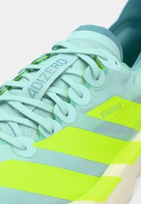 Svijetloplave atletske tenisice s teksturiranim gornjim dijelom, s izraženim žutim prugama i oznakom "ADIZERO" na jeziku.