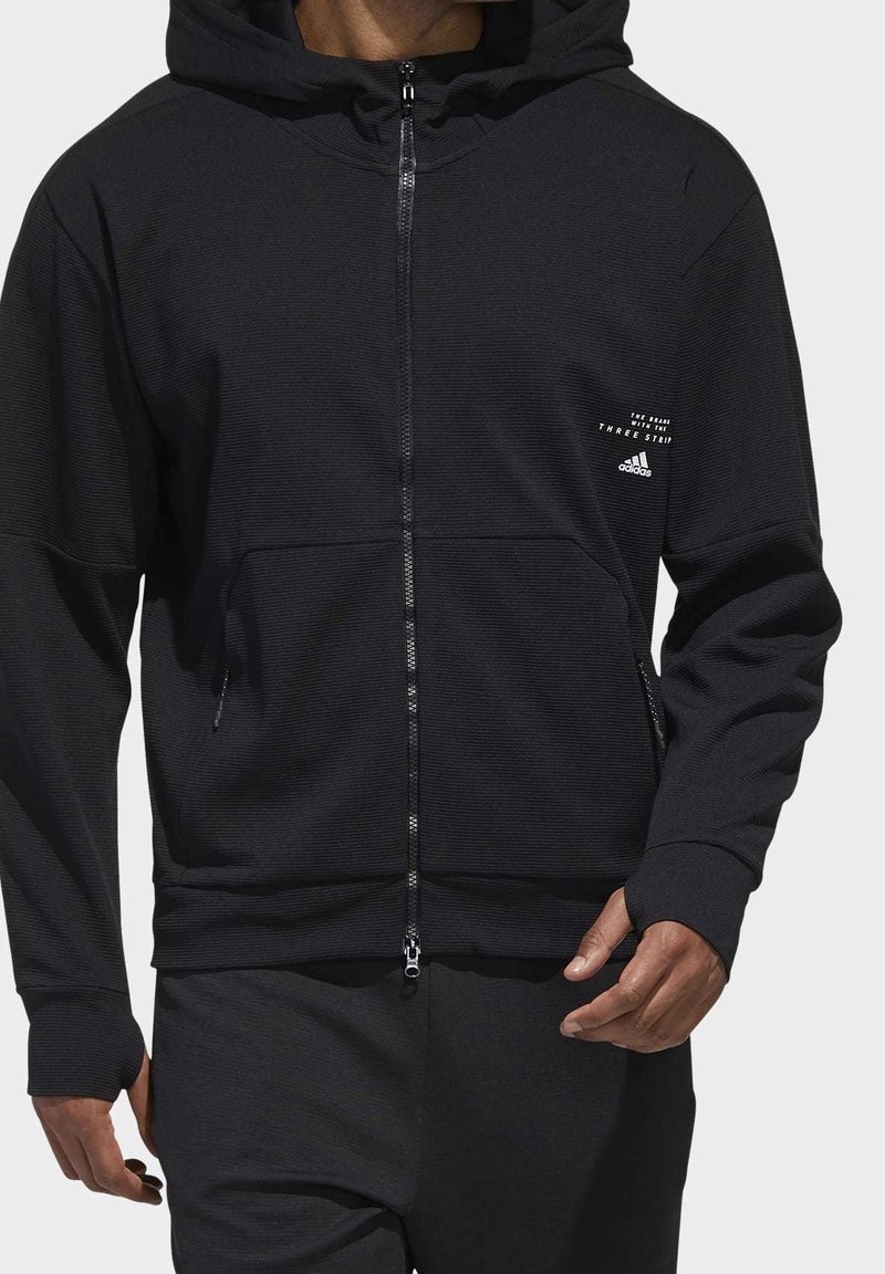 Svart zip-up hoodie med en texturerad tyg, med sidofickor och en framsida med logotyp. Design av pullover med en stor huva och ribbade manschetter.