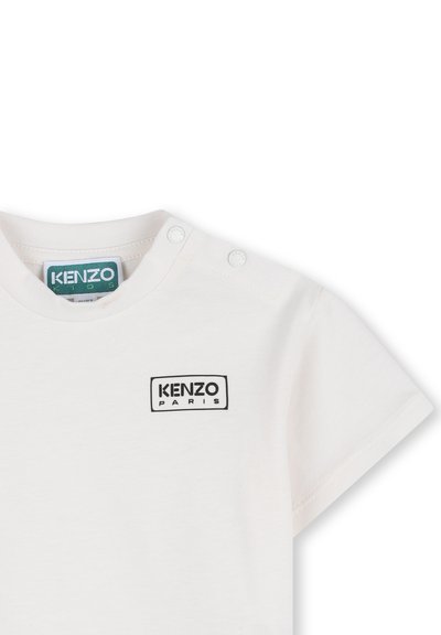 Witte katoenen T-shirt met korte mouwen, voorzien van een klein zwart rechthoekig logo met "KENZO PARIS" op de borst en twee drukknopen op de schouder.