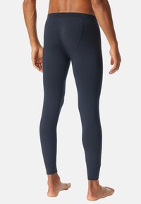 Marinblå långunderställ tillverkat av ett mjukt, elastiskt material, med en kroppsnära design, sömlöst midjeband och ribbade muddar vid anklarna.