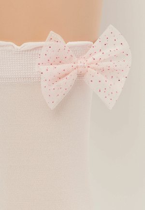 Calzini rosa chiaro con una texture a coste e bordo ondulato, impreziositi da un fiocco trasparente rosa con pois rossi e rosa sul lato.