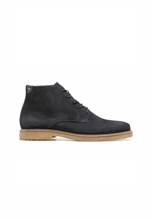 Bottines en suède bleu foncé avec un bout arrondi, un design à lacets et une semelle en caoutchouc contrastante marron clair. Logo embossé sur le côté.