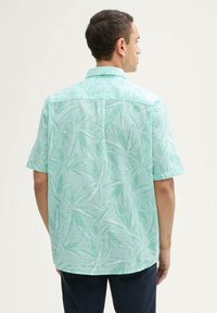 Korte mouwen shirt in lichtgroen met een bladpatroon. Gemaakt van een gestructureerde stof, met een kraag en een achterste schoudernaad.