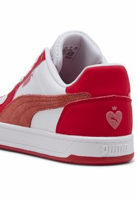 Baskets rouge et blanc avec une bande latérale en daim, talon rouge texturé et logo embossé. Tige en cuir lisse avec col rembourré.