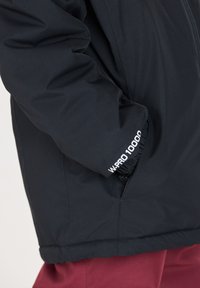 Schwarze isolierte Jacke mit glatter Textur, elastischen Bündchen mit "W PRO 10000" Branding und einer taillierten Passform an der Taille.